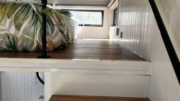 A compact room with a bed, a small window, and a white toilet.