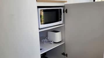 Une cuisine avec un four à micro-ondes sur l’étagère supérieure, un grille-pain sur l’étagère du milieu et une casserole sur l’étagère inférieure.