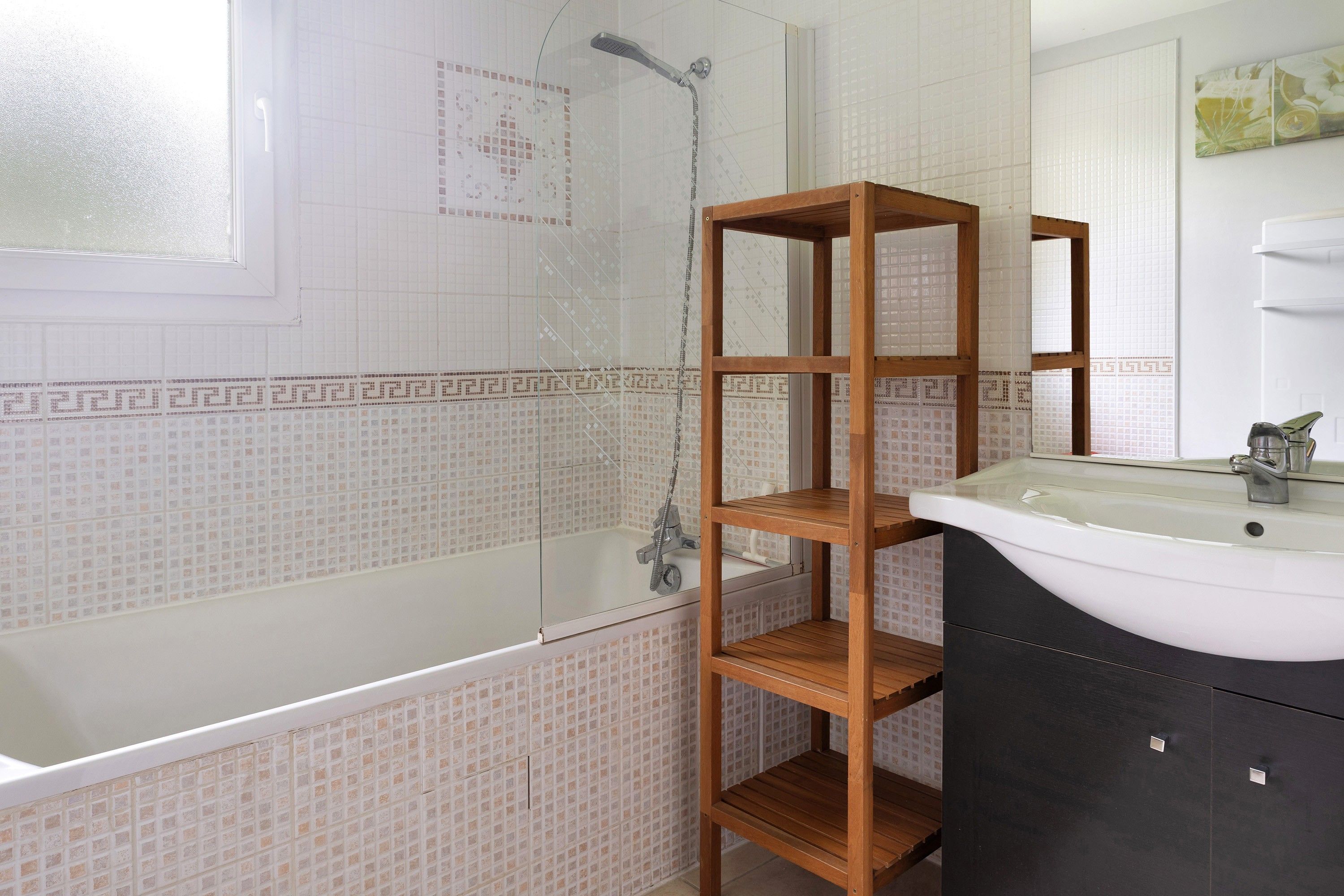 Une salle de bain avec une baignoire, une étagère en bois et un lavabo.