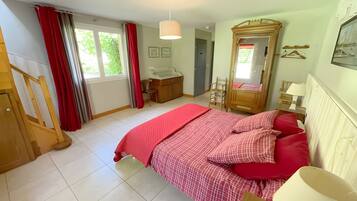Een slaapkamer met een bed, een dressoir, een spiegel en een raam met gordijnen.