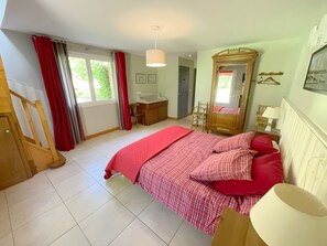 Une chambre à coucher avec un lit, une commode, un miroir et une fenêtre avec des rideaux.