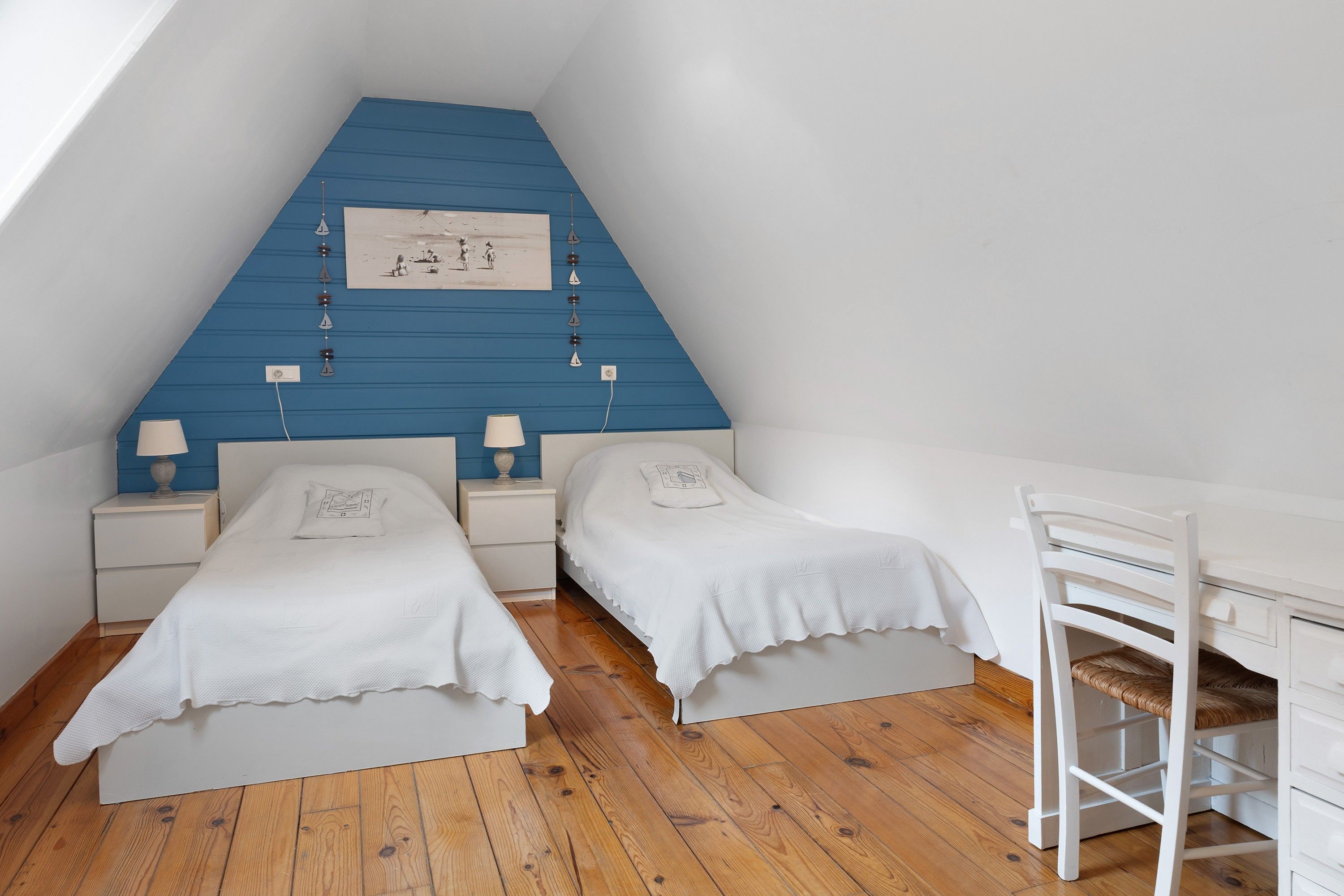 A bedroom with two single beds, a desk, and a chair.