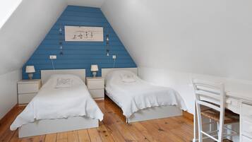 A bedroom with two single beds, a desk, and a chair.