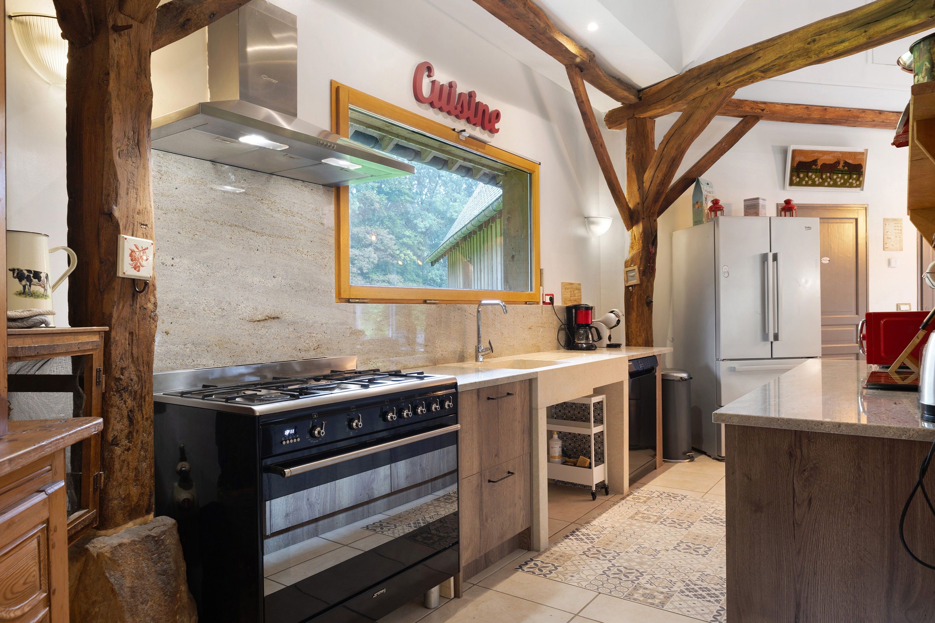 Cozinha com fogão, forno e janela com vista para um jardim.