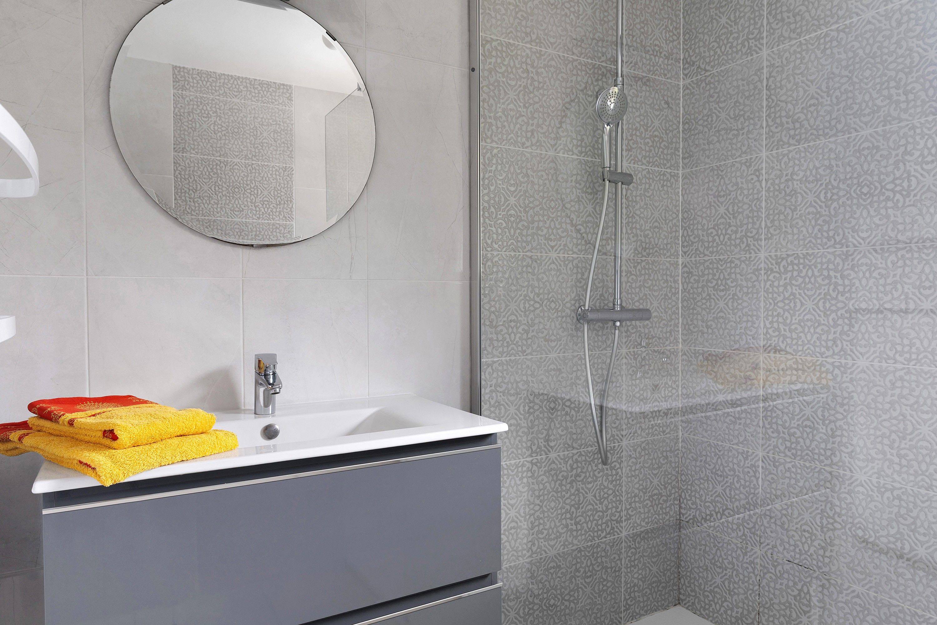 A bathroom with a shower, a sink, and a mirror.