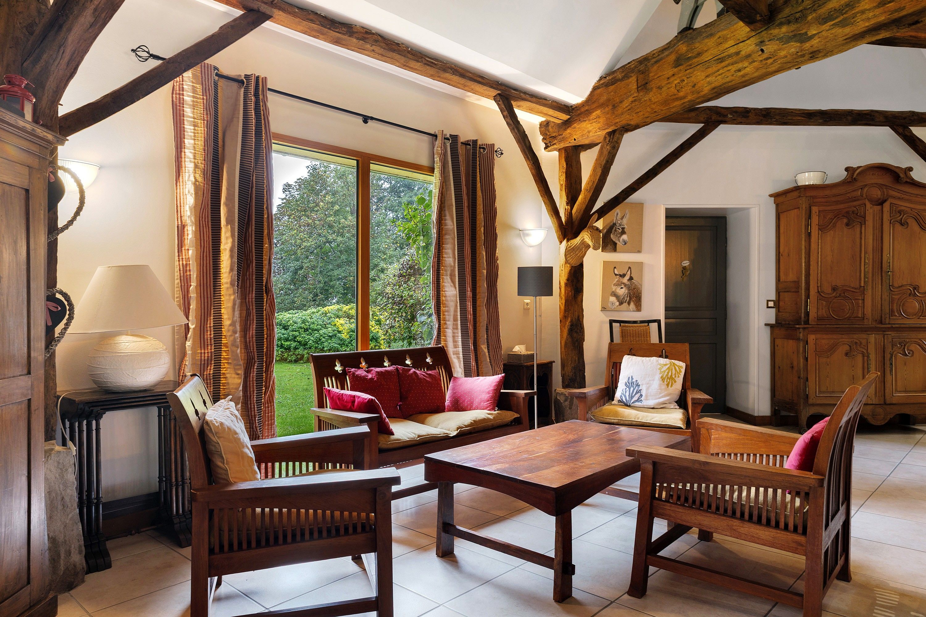 Un intérieur rustique avec des poutres apparentes, une table en bois et un canapé agrémenté de coussins.