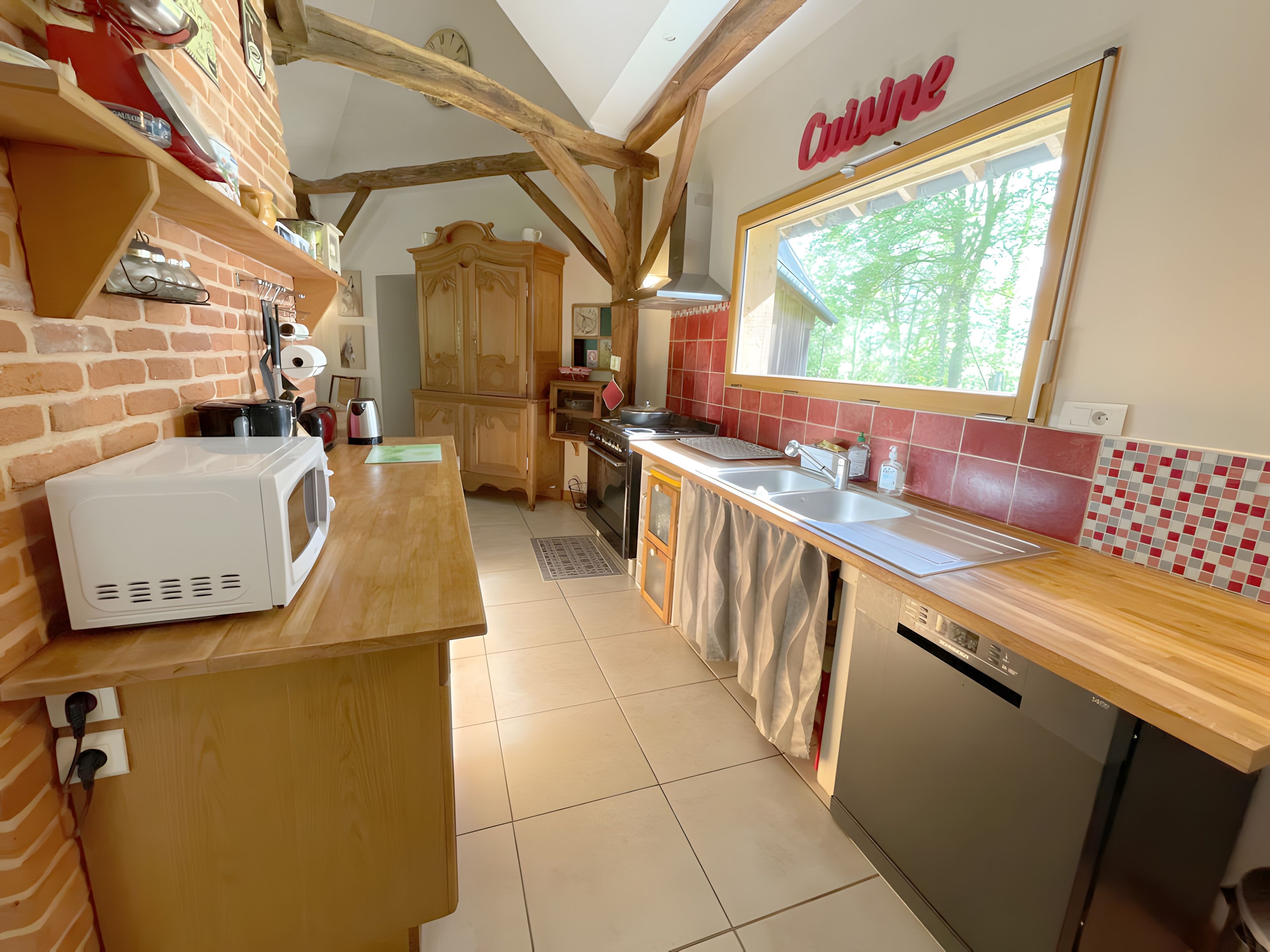 Een keuken met een houten aanrecht, een witte magnetron, een spoelbak en een vaatwasser.