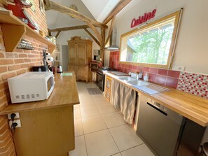 Une cuisine avec un plan de travail en bois, un micro-ondes blanc, un évier et un lave-vaisselle.