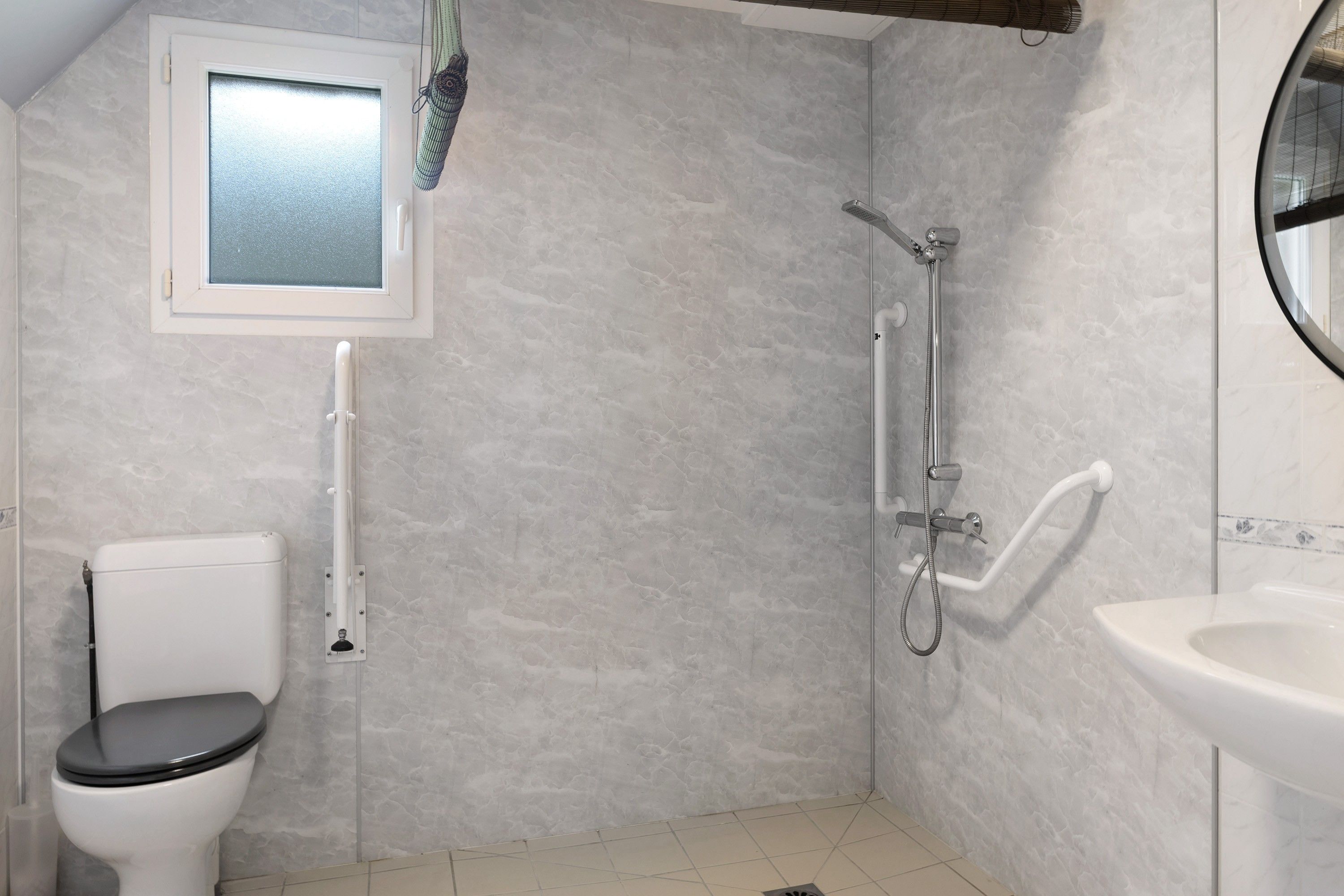 A bathroom with a toilet, a shower, and a sink.