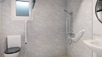 A bathroom with a toilet, a shower, and a sink.