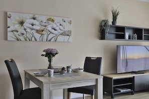A dining area with a wooden table, black chairs, a vase with flowers, and a painting on the wall. - Holiday apartment Ostseewoge (Ostseebad Nienhagen)