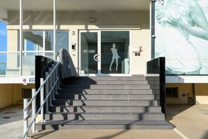 A staircase leading to a building entrance with a glass door and a silhouette of a woman. - A modern, bright 40-square-meter apartment suitable for three people, located on the fifth floor of a seaside residential complex (elevator available, though, not suitable for people with disabilities; there is a flight of stairs at the entrance and addi (Viserbella)