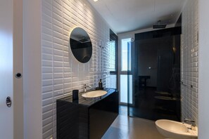 Une salle de bain moderne avec un meuble-lavabo noir, un miroir rond et une douche à l’italienne.