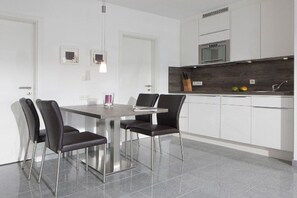 A modern kitchen with white cabinets, a stainless steel countertop, and a built-in oven. - Seilerstr./Knyphausenstr.26A - Fiene (Norderney)