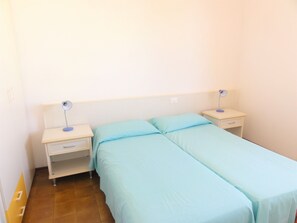 A room with two single beds, each with a nightstand and a lamp. There is a small drawer under one nightstand. - Nice flat with shared pool (Bibione)