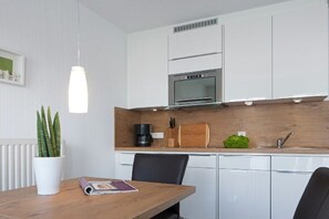 Una cucina moderna con mobili bianchi, forno integrato e piano di lavoro in legno.