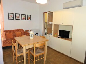 A compact living space with a dining table, chairs, a sofa, a washing machine, and a TV. - Peaceful village with pool (Bibione)
