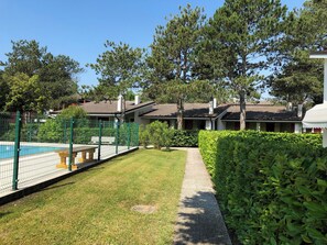 A residential area with a swimming pool, a fenced patio, and a well-maintained lawn. - Charming terraced villa (Bibione)