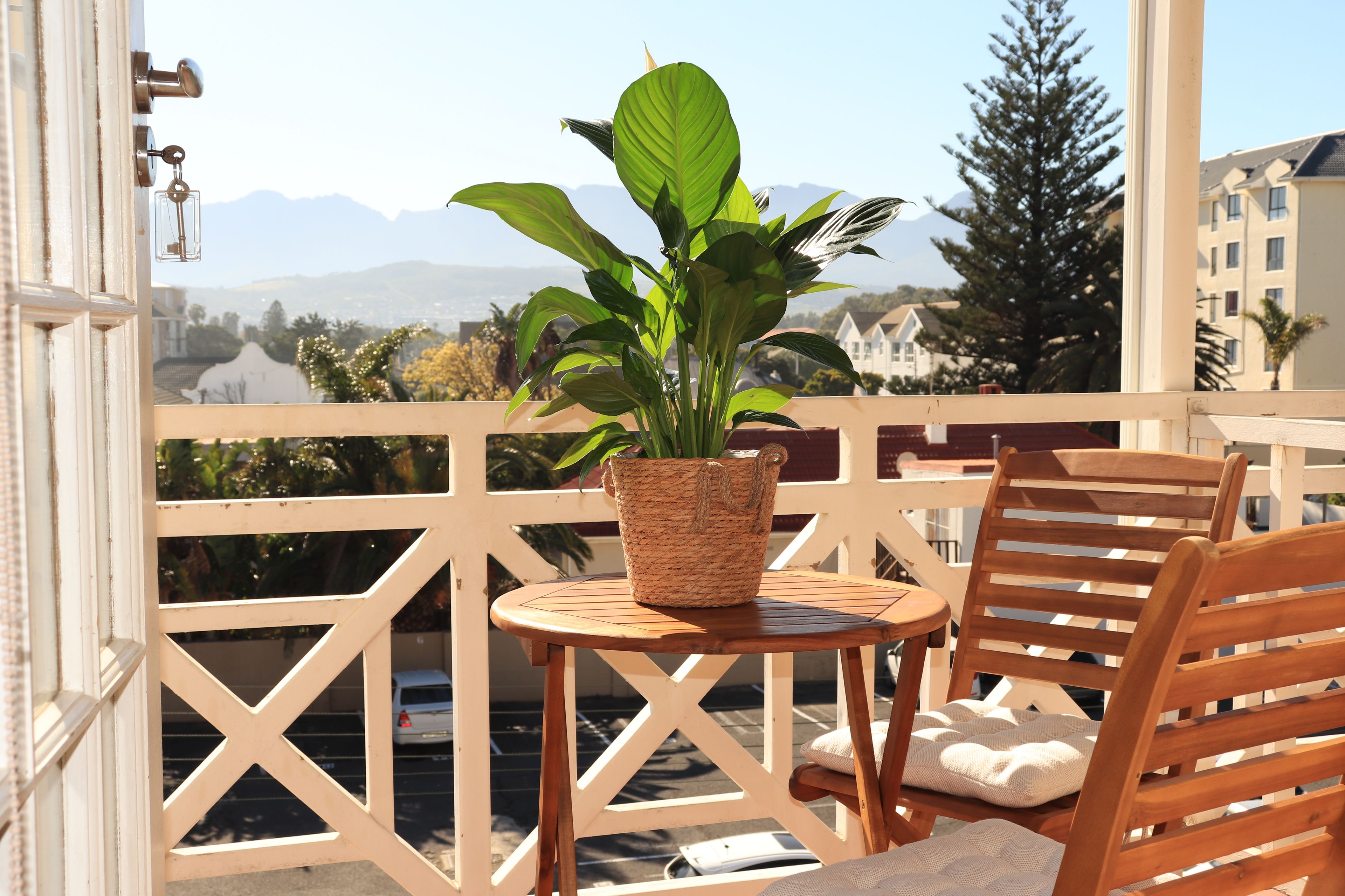 Een balkon met een houten stoel, een tafeltje en een potplant.