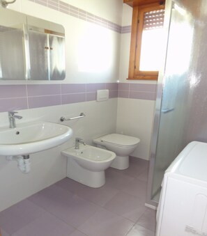 Un baño con lavamanos, bidé, inodoro y zona de ducha.