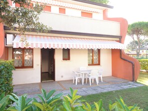 Une maison à deux étages dotée d’un patio couvert, d’une table à manger et de chaises.