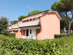 Un bâtiment à deux étages, doté d’un toit plat, d’un balcon avec des balustrades blanches, et d’une petite table et des chaises à l’extérieur.
