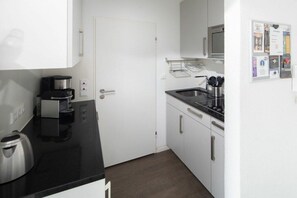 A compact kitchen with a coffee maker, a microwave, and a sink. - Holiday apartment in Norderney with Wi-Fi (Norderney)