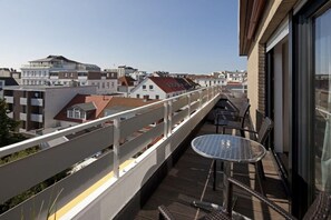 A balcony with a table and chairs, overlooking a cityscape with buildings. - Holiday apartment in Norderney with Wi-Fi (Norderney)