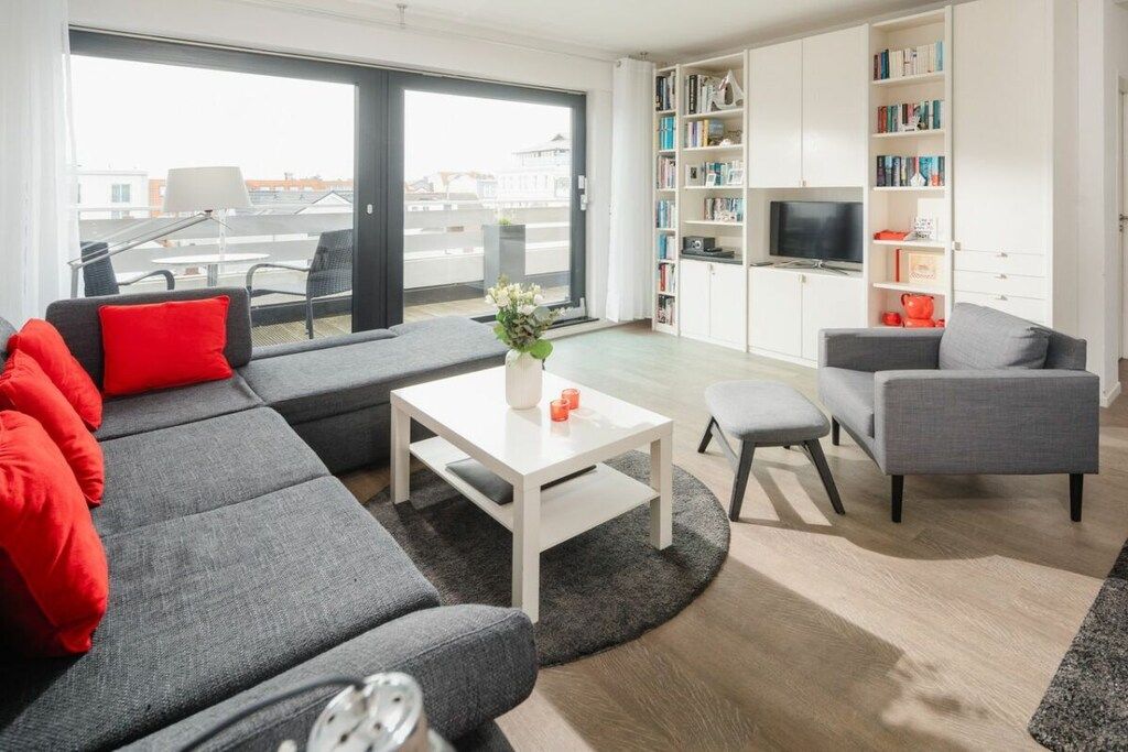 Un salon moderne avec un canapé gris, une table basse blanche et une bibliothèque.