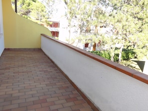 Un balcó amb un paviment de maó i una paret blanca amb adorn de color vermell.