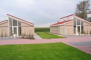 A modern building with a flat roof, large windows, and a paved walkway. - Holiday home with 1 bedroom (Burgerbrug)