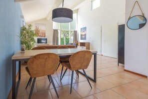 A modern kitchen with a dining table and chairs, a hanging light fixture, and a view to the outside. - Holiday home with 1 bedroom (Burgerbrug)