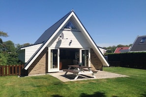 Ein dreieckiges Haus mit Terrasse und Picknicktisch.