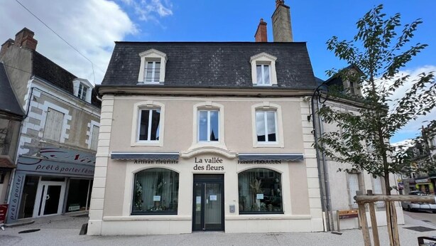 Um edifício de dois andares com uma placa que diz 'La vallée des fleurs' e 'Artisan fleuret'.