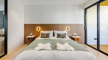 Quarto de hotel moderno com uma cama grande, duas mesas de cabeceira e uma janela ampla.