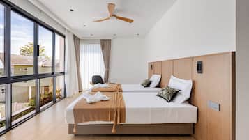 A hotel room with two beds, large windows, a ceiling fan, and a view of the outside.