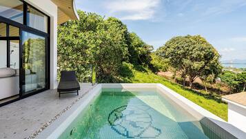 A modern outdoor swimming pool with a clear view of the surrounding greenery and a distant landscape.
