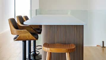 Uma área de bar moderna com uma ilha central, banquetas e iluminação pendente.