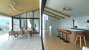 Une cuisine moderne avec des tabourets de bar en bois, un coin repas avec des chaises et de grandes fenêtres.