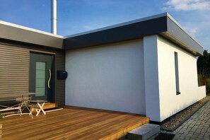 A modern house with a wooden deck, a chimney, and a white exterior wall. - Strandhaus Treibgut new in 2015 (Großenbrode)