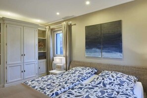 A bedroom with a bed, a wardrobe, a window with curtains, and a painting on the wall. - Strandhaus Treibgut new in 2015 (Großenbrode)