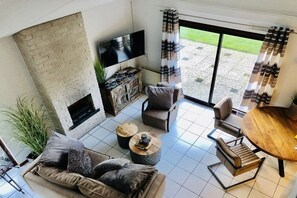 Una sala de estar moderna con chimenea, asientos cómodos, un televisor de pantalla plana y vistas al exterior.