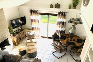 A living room with a flat-screen TV, a sofa, a coffee table, and a dining area with chairs and a table. - Holiday home in Julianadorp with Wi-Fi (Julianadorp)