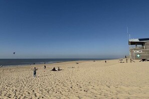 A beach with a lifeguard tower, sandy beach, and a clear sky. - Holiday home in Julianadorp with Wi-Fi (Julianadorp)