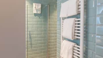 A bathroom with a glass shower enclosure, a white towel rack, and a tiled wall.