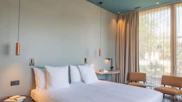 Une chambre d’hôtel avec un grand lit, une table de chevet, une lampe, deux chaises et une vue sur l’extérieur par la fenêtre.