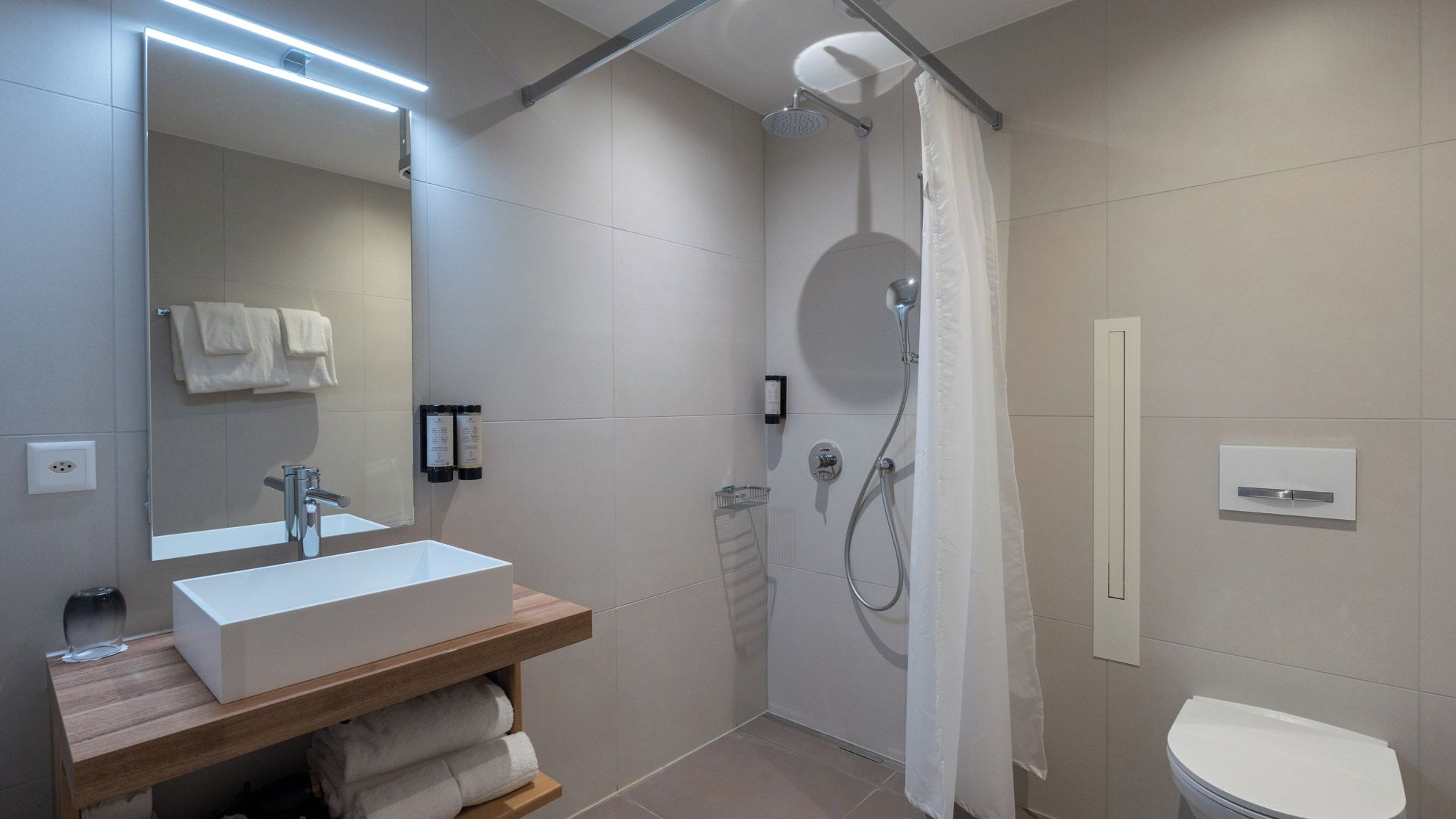 Une salle de bain moderne avec un lavabo blanc, un miroir et une douche.