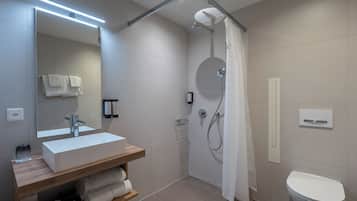 Une salle de bain moderne avec un lavabo blanc, un miroir et une douche.