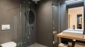 A modern bathroom with a glass-enclosed shower, a white toilet, and a wooden vanity with a mirror.