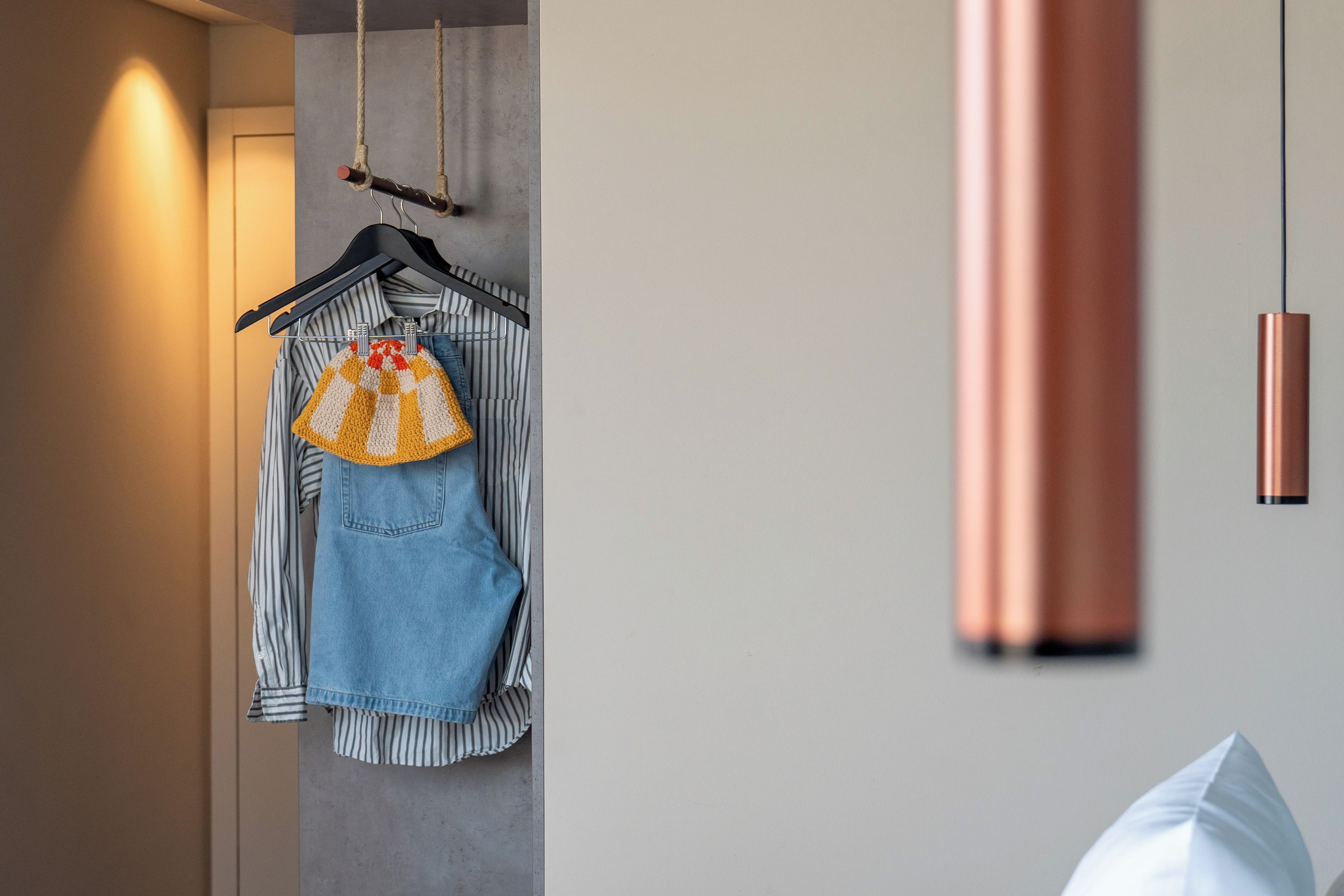 A room with a hanging garment on a black hanger, a striped shirt, and a denim skirt.